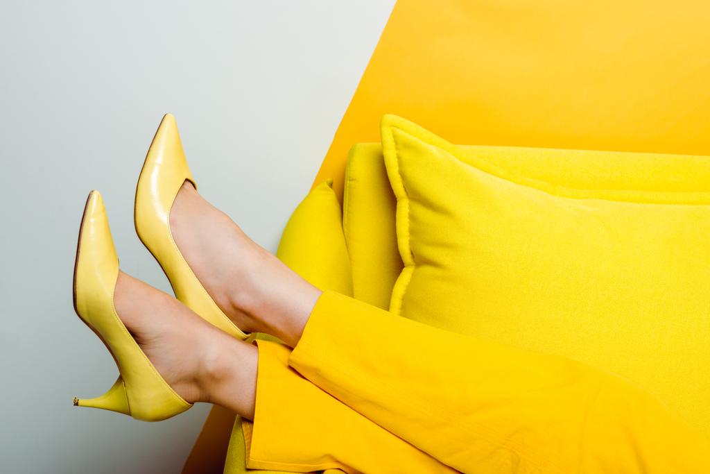 abgeschnittene Ansicht einer Frau in High Heels in der Nähe von Kissen auf weiß und gelb  - Foto, Bild