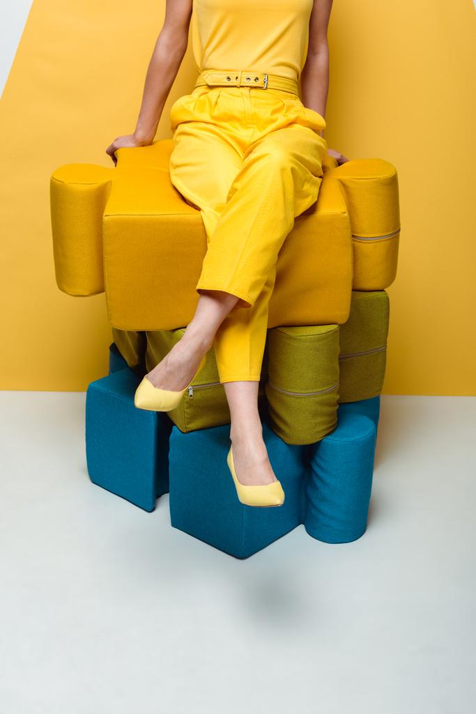 oříznutý pohled ženy sedící na velkých měkkých figuríně na bílém a žlutém  - Fotografie, Obrázek