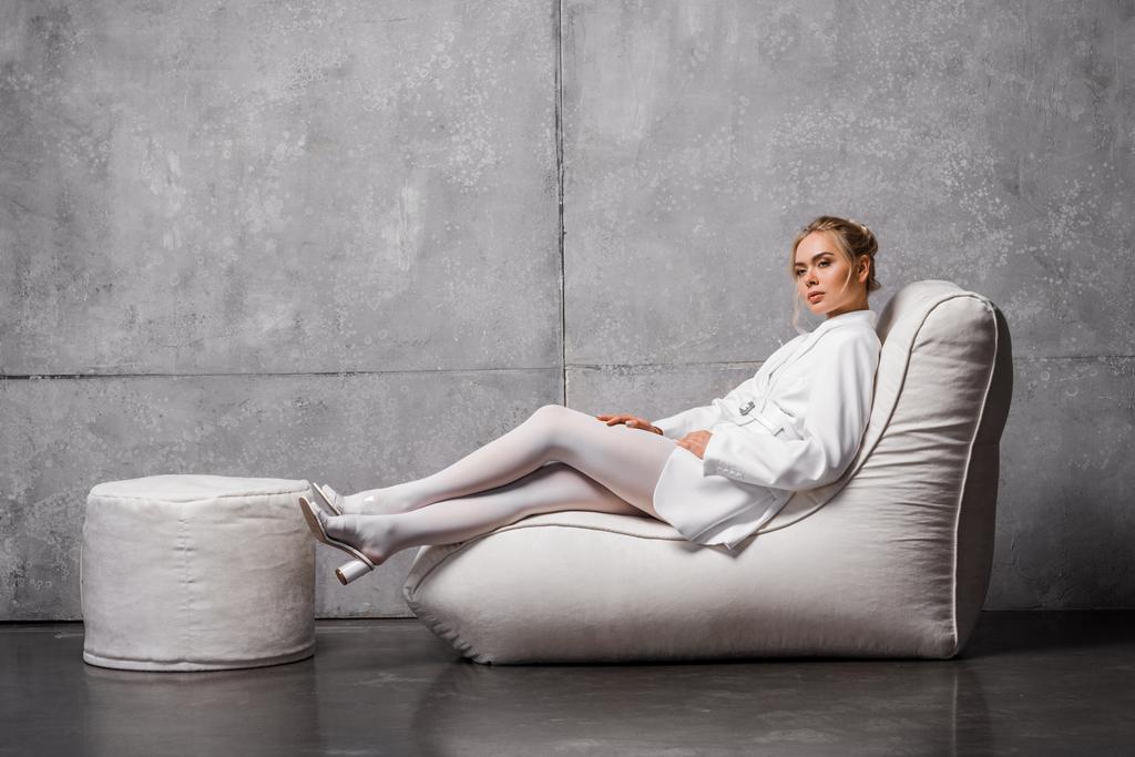 jolie femme blonde assise sur une chaise de sac de haricot doux sur gris
  - Photo, image