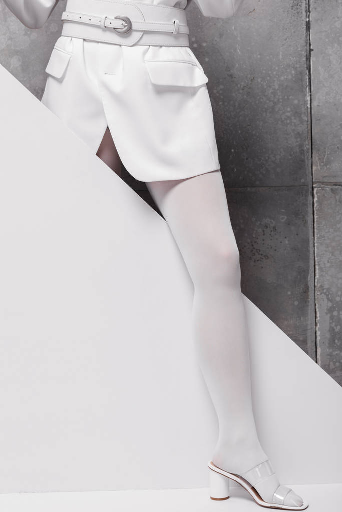 abgeschnittene Ansicht einer stilvollen Frau in Schuhen, die auf weiß und grau posiert - Foto, Bild