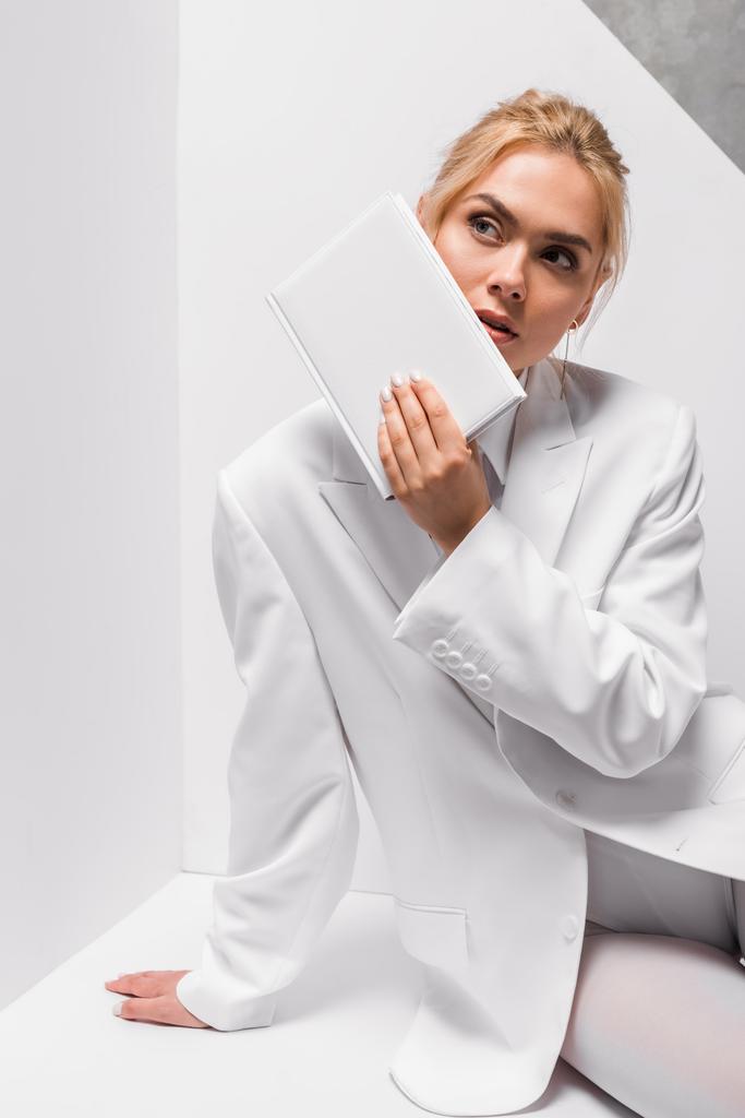 Blondýnka s prázdným poznámkovým blokem na bílém a šedém  - Fotografie, Obrázek