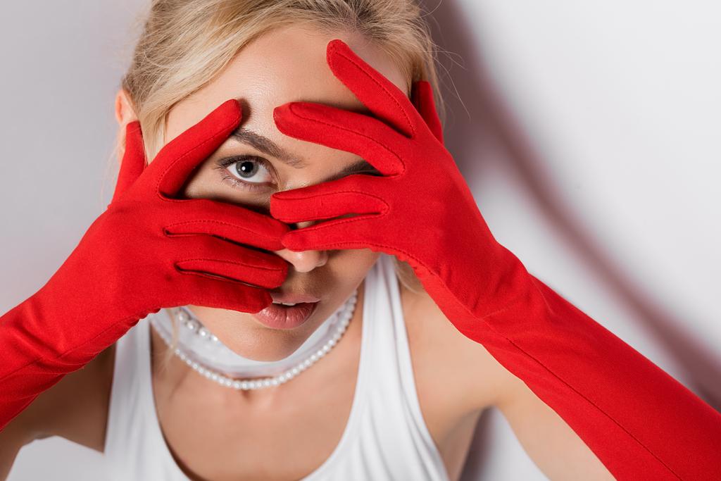 jovem loira em luvas vermelhas cobrindo rosto em branco
  - Foto, Imagem