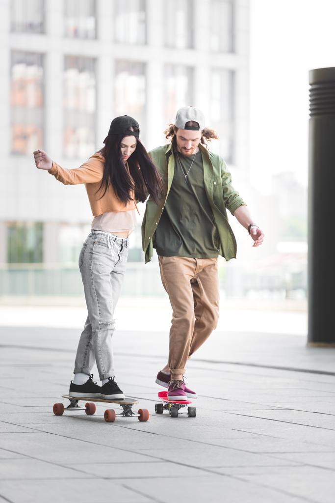 couple heureux en tenue décontractée chevauchant sur des planches à roulettes en ville
 - Photo, image