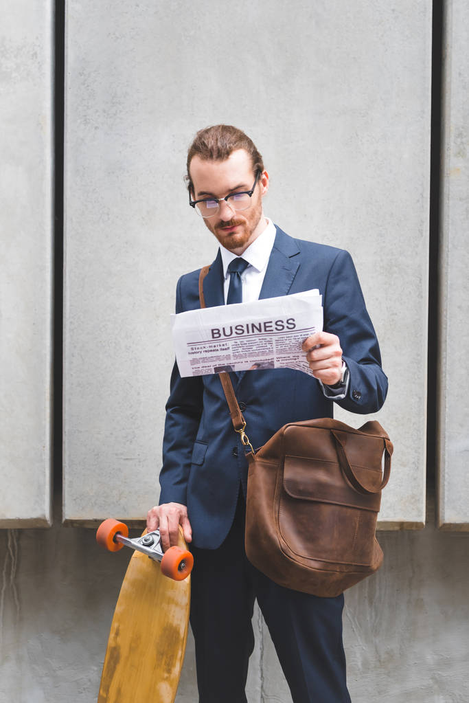 hombre de negocios en ropa formal con monopatín en periódico de lectura manual
 - Foto, imagen