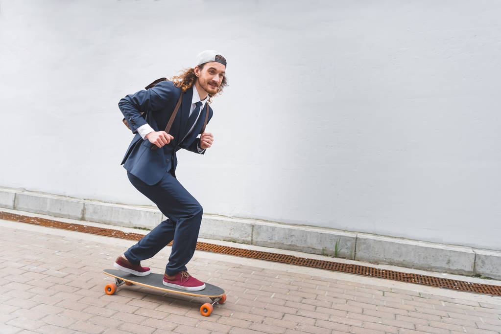 heureux et beau homme d'affaires chevauchant sur skateboard à la rue
 - Photo, image