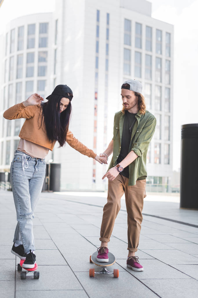 bell'uomo che si tiene per mano con una donna bruna, indicando il dito allo skateboard
 - Foto, immagini