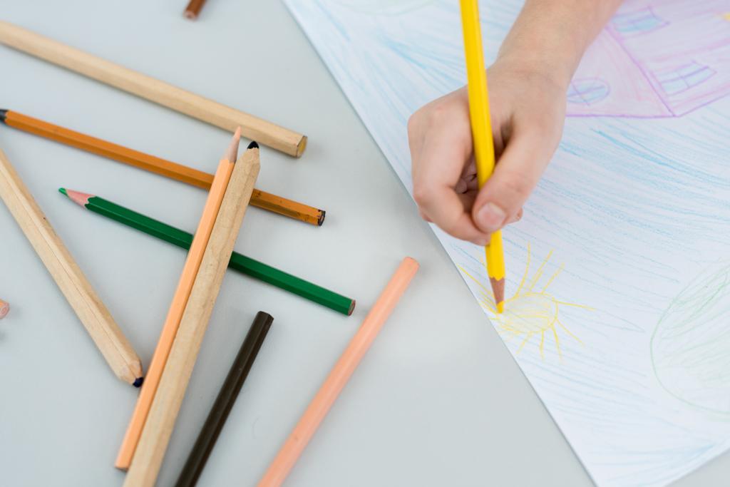 обрізаний вид малюнка дитини з жовтим олівцем на папері
  - Фото, зображення