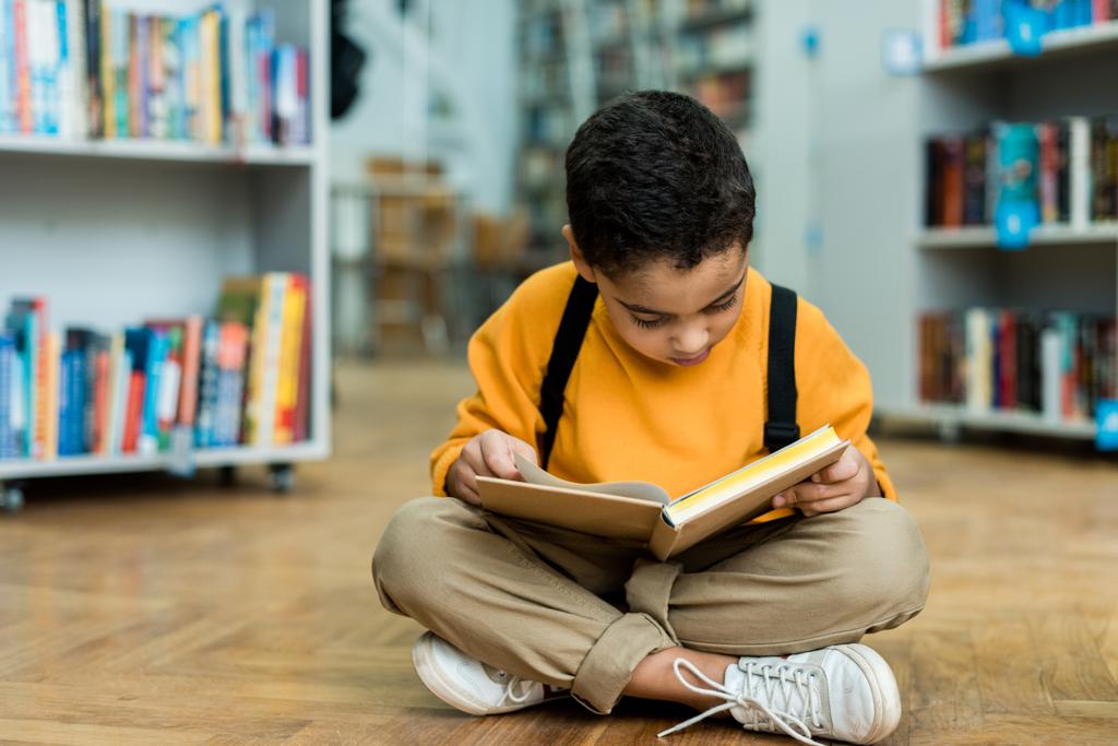 słodkie African American chłopiec siedzi na podłodze i czytania książki  - Zdjęcie, obraz