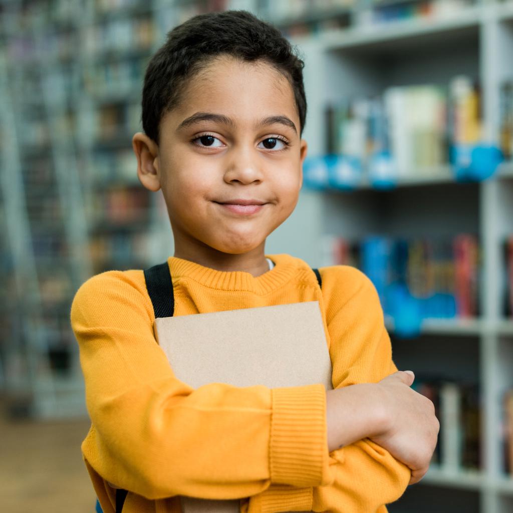bonito afro-americano menino sorrindo enquanto segurando livro
  - Foto, Imagem