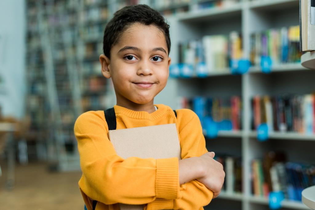 roztomilý Afroameričan kluk držící knížku a pohled na kameru  - Fotografie, Obrázek