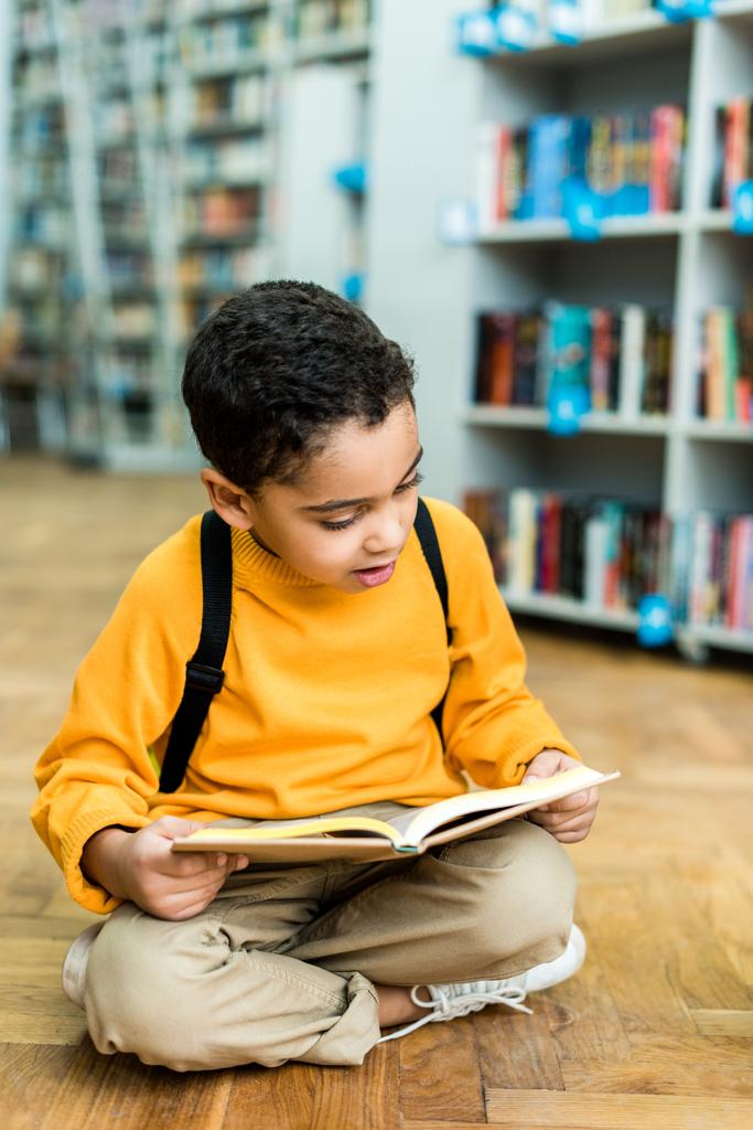 adorável menino afro-americano sentado no chão e livro de leitura
  - Foto, Imagem
