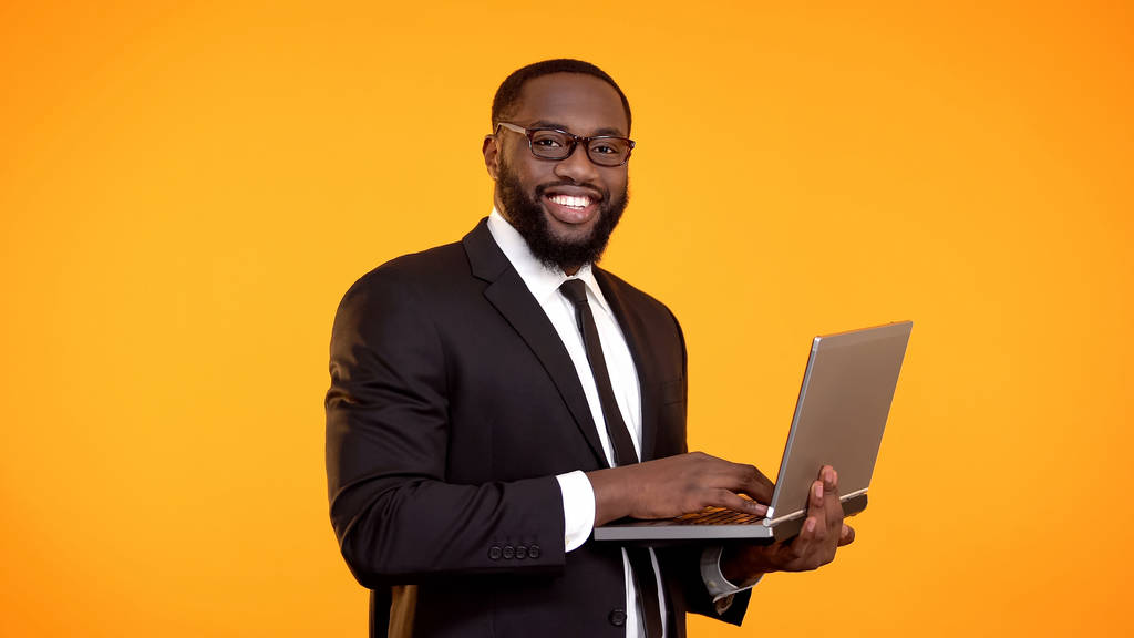 Uomo d'affari afro-americano sorridente che lavora su laptop, crescita di carriera, affari
 - Foto, immagini