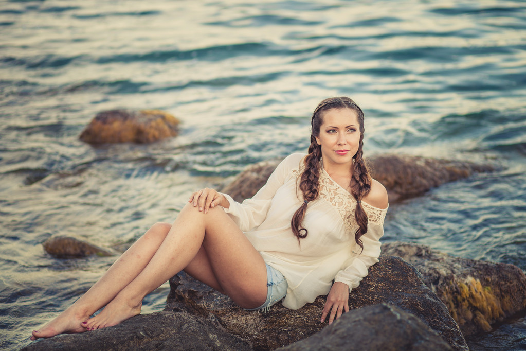deniz kıyısı taşa oturup güzel bir genç kadın - Fotoğraf, Görsel