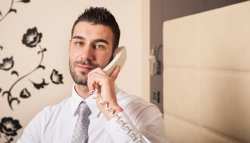 Jeune homme d'affaires parlant au téléphone dans la chambre d'hôtel
. - Photo, image