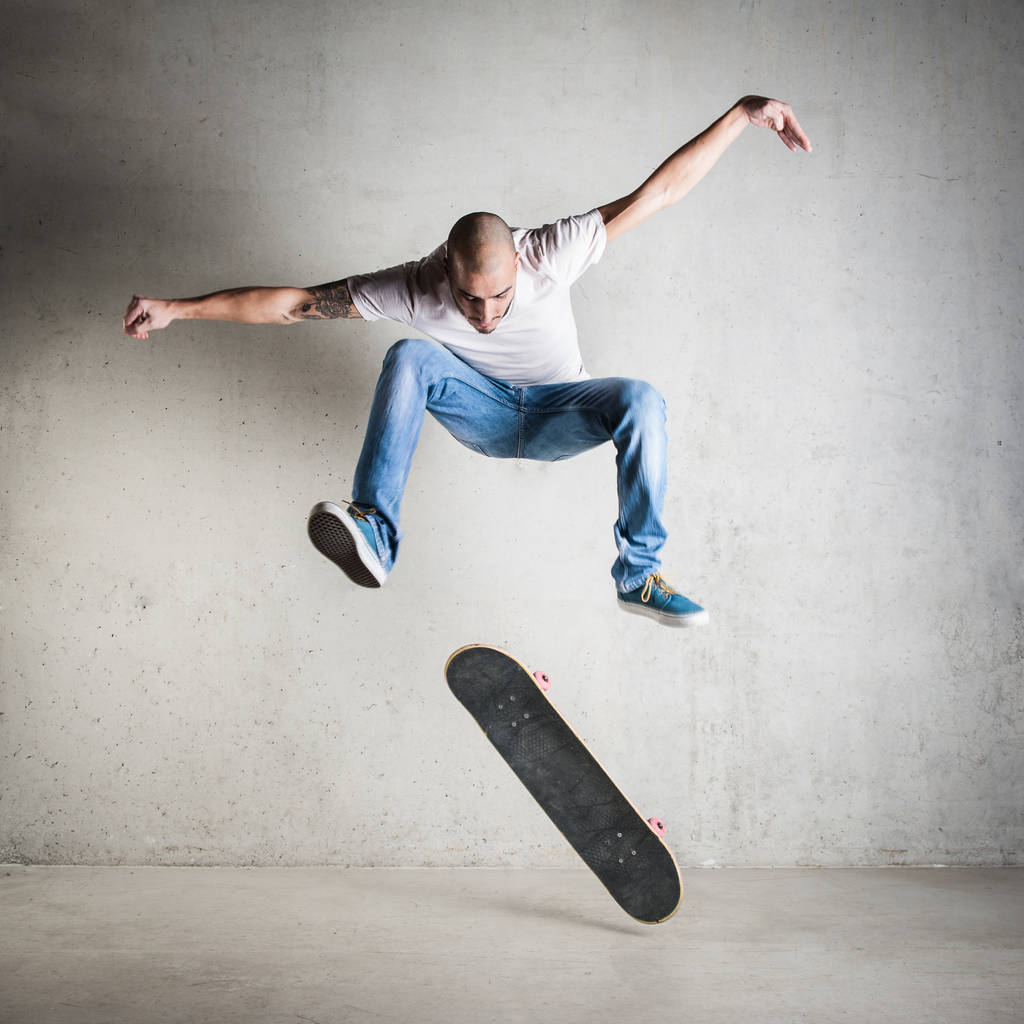コンクリートの壁に飛び乗るスケートボーダー.  - 写真・画像