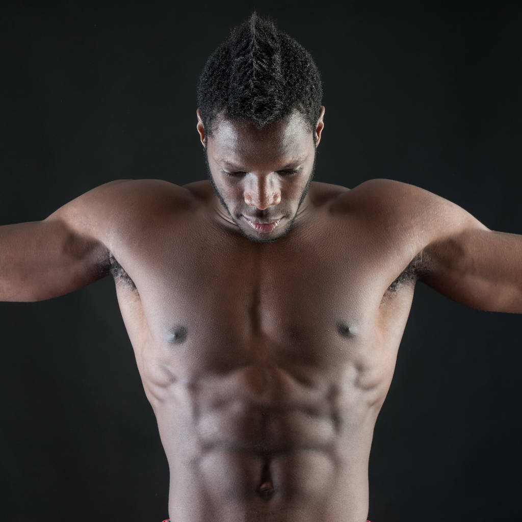 Ισχυρός νέος άντρας με γυμνό πουκάμισο με μαύρο φόντο.  - Φωτογραφία, εικόνα