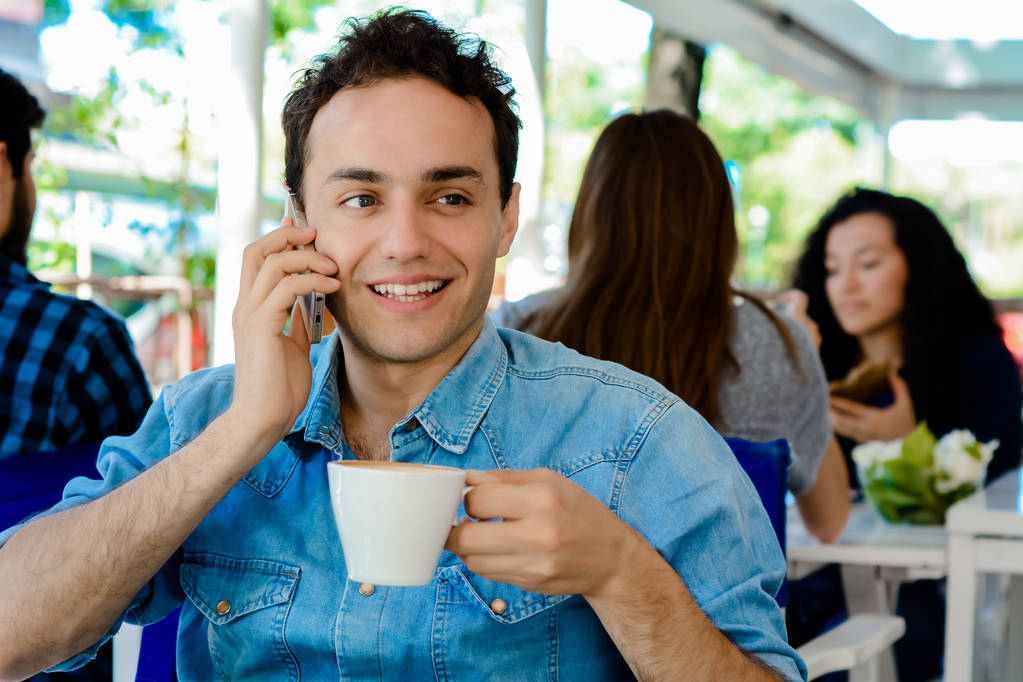 Ο άνθρωπος χρησιμοποιώντας το κινητό τηλέφωνο και πίνοντας τον καφέ - Φωτογραφία, εικόνα
