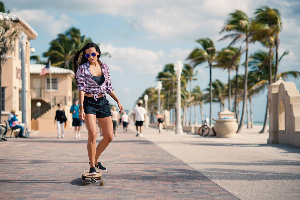 Sportowa młoda kobieta jeździ długą planą na hollywoodzkiej plaży w Miami na Florydzie. Obraz filtrowany. - Zdjęcie, obraz