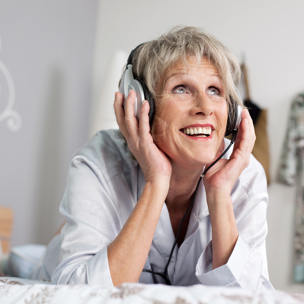 γυναίκα που ακούτε μουσική μέσα από το ακουστικό στο κρεβάτι - Φωτογραφία, εικόνα