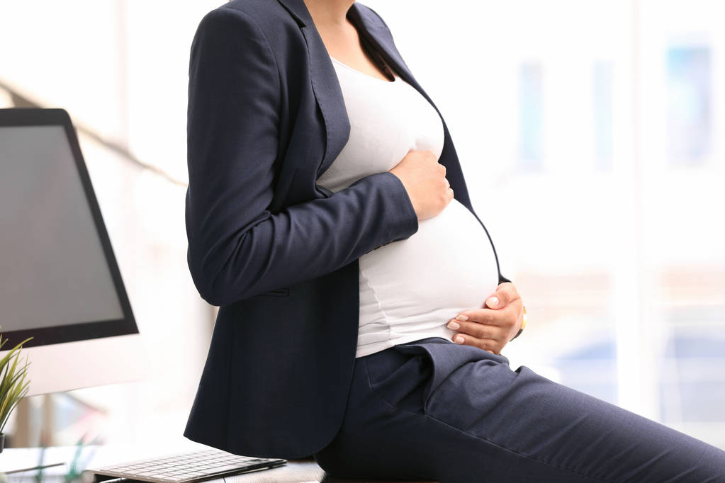 Νεαρή έγκυος γυναίκα με κοστούμι στο χώρο εργασίας, κοντινό πλάνο - Φωτογραφία, εικόνα