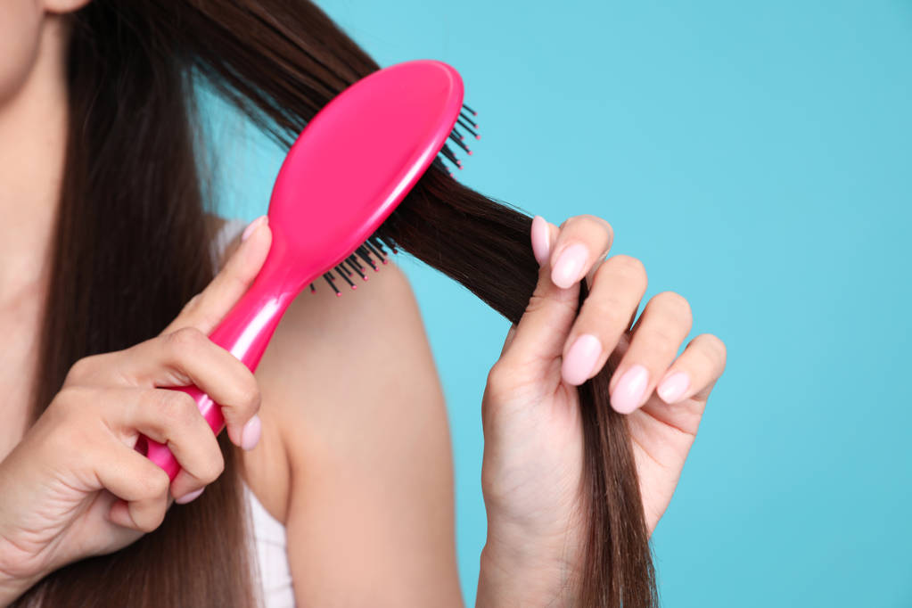 Mujer con cepillo de pelo sobre fondo de color, primer plano. Espacio para texto
 - Foto, Imagen