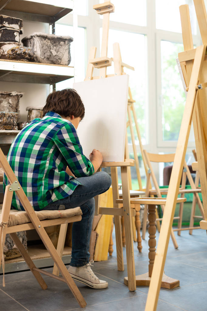 Écolier assis près de la fenêtre et la peinture à l'école d'art
 - Photo, image