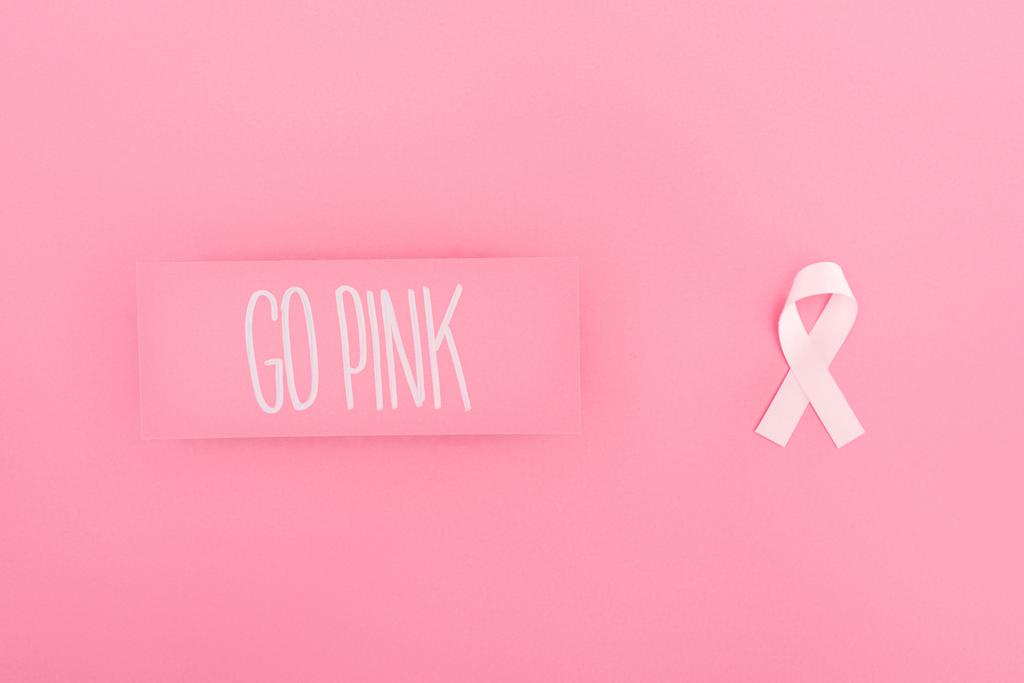 felülnézet megy rózsaszín betűkkel a kártya és a mellrák jel rózsaszín háttér - Fotó, kép