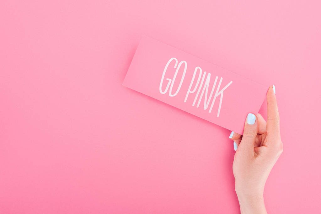 vista parziale della donna in possesso di carta con go lettering rosa su sfondo rosa
 - Foto, immagini