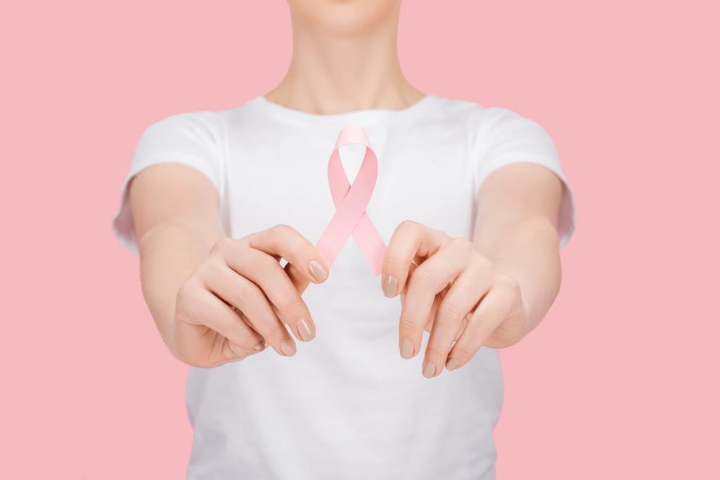 visión parcial de la mujer en camiseta blanca sosteniendo signo de cáncer de mama rosa aislado en rosa
 - Foto, imagen