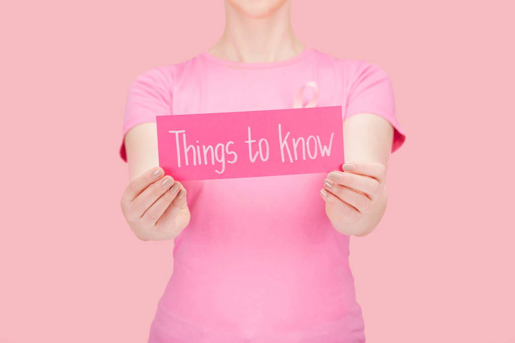 селективное внимание женщины в розовой футболке держа карточку с вещами, чтобы знать буквы изолированы на розовый, рак молочной железы концепции
 - Фото, изображение