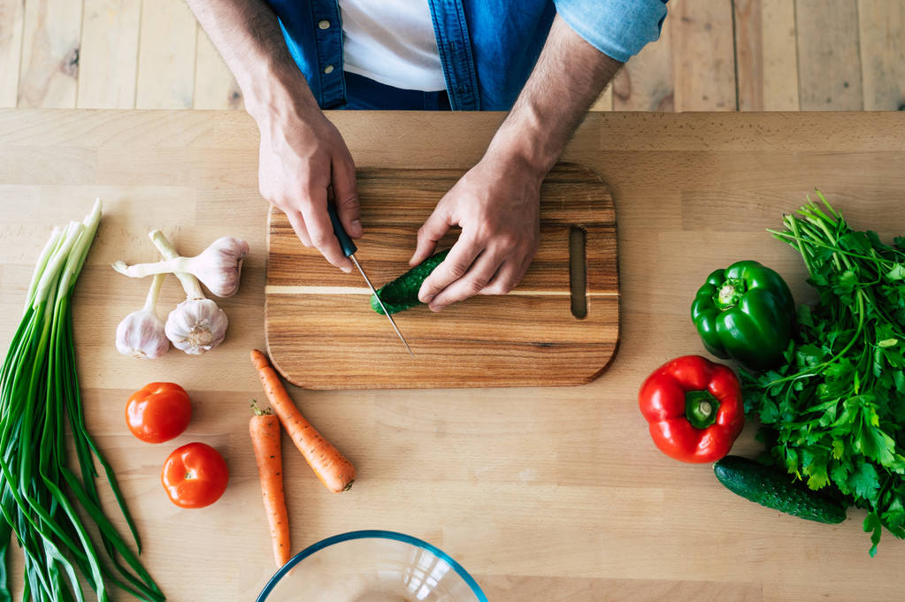 Man cooking healthy food. Fresh vegetables on the cutting board. Concept of cooking. Diet. Healthy and vegan lifestyle. Cooking at home. Prepare food. Male hands cutting vegetables in the kitchen - Photo, Image