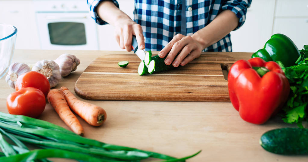 Weibliche Hände schneiden Gemüse in der Küche. Frau, die gesunde Nahrung kocht. frisches Gemüse auf dem Schneidebrett. Kochkonzept. Ernährung. gesunde und vegane Lebensweise. Kochen zu Hause. Essen zubereiten - Foto, Bild