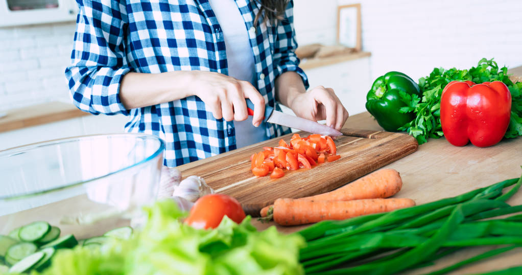 台所で野菜を切る女性の手。健康的な食べ物を調理する女性。まな板の上の新鮮な野菜。料理の概念。ダイエット。健康的でビーガンなライフスタイル。自宅で料理。食べ物の準備 - 写真・画像