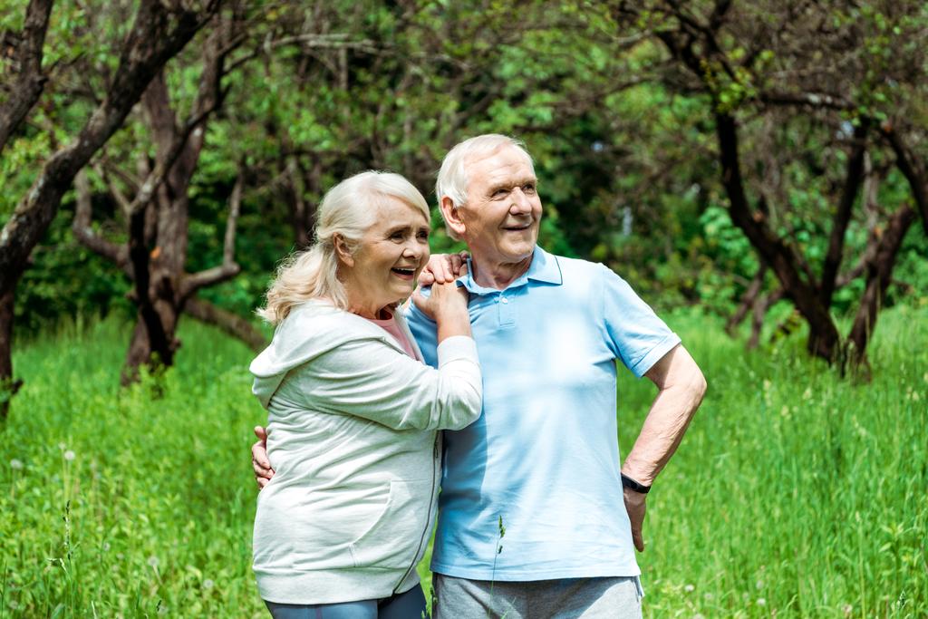 cheerful senior man standing with hand on hip near wife  - Photo, Image