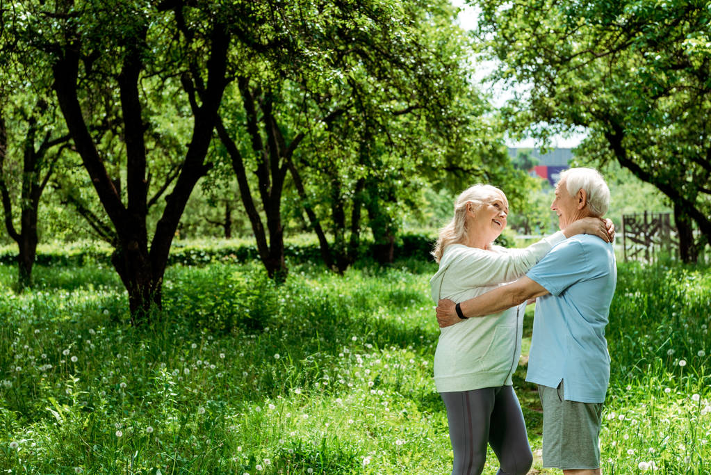 緑の公園で先輩妻を抱きしめる陽気な引退した男  - 写真・画像