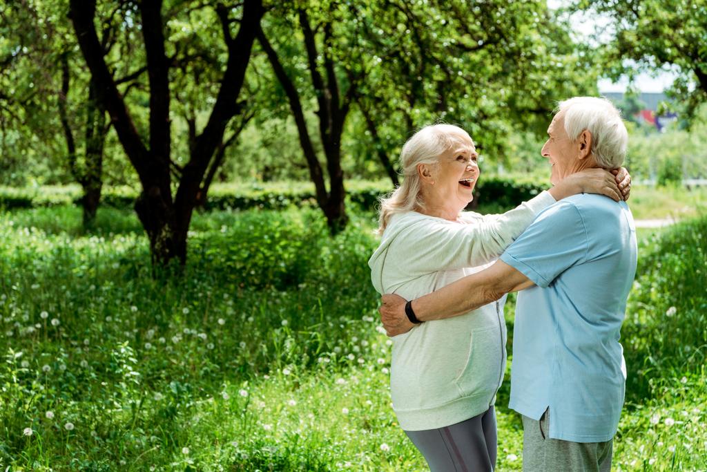 緑の公園で先輩妻を抱きしめる幸せな引退した男  - 写真・画像