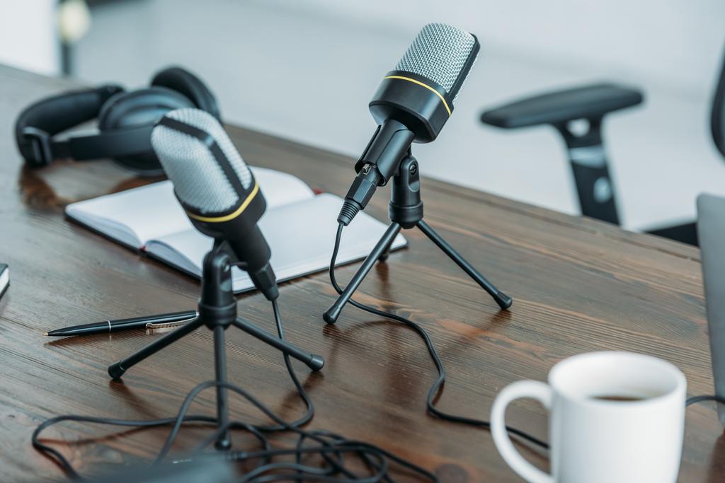 selectieve focus van twee microfoons om houten tafel in omroep studio - Foto, afbeelding