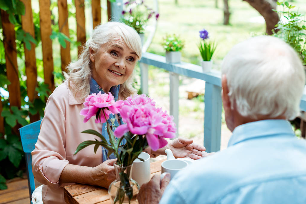 selective focus of happy senior woman looking at husband near pink flowers  - Photo, Image