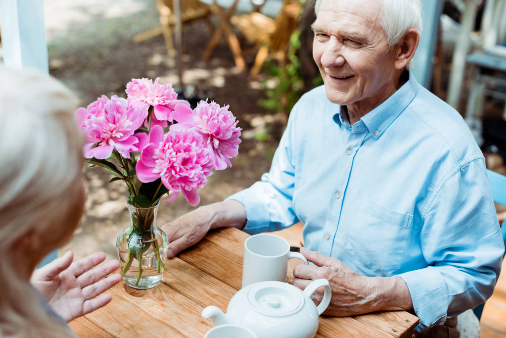 селективное внимание счастливого пожилого мужчины, держащего кубок и смотрящего на жену
  - Фото, изображение
