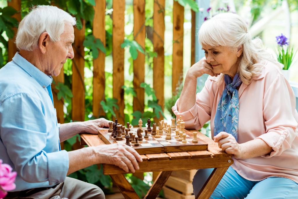συνταξιούχος γυναίκα με γκρίζα μαλλιά παίζοντας σκάκι με τον ανώτερο άντρα - Φωτογραφία, εικόνα