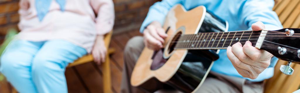 panoráma szemcsésedik-ból idősebb ember játék akusztikus gitár mellett feleség  - Fotó, kép