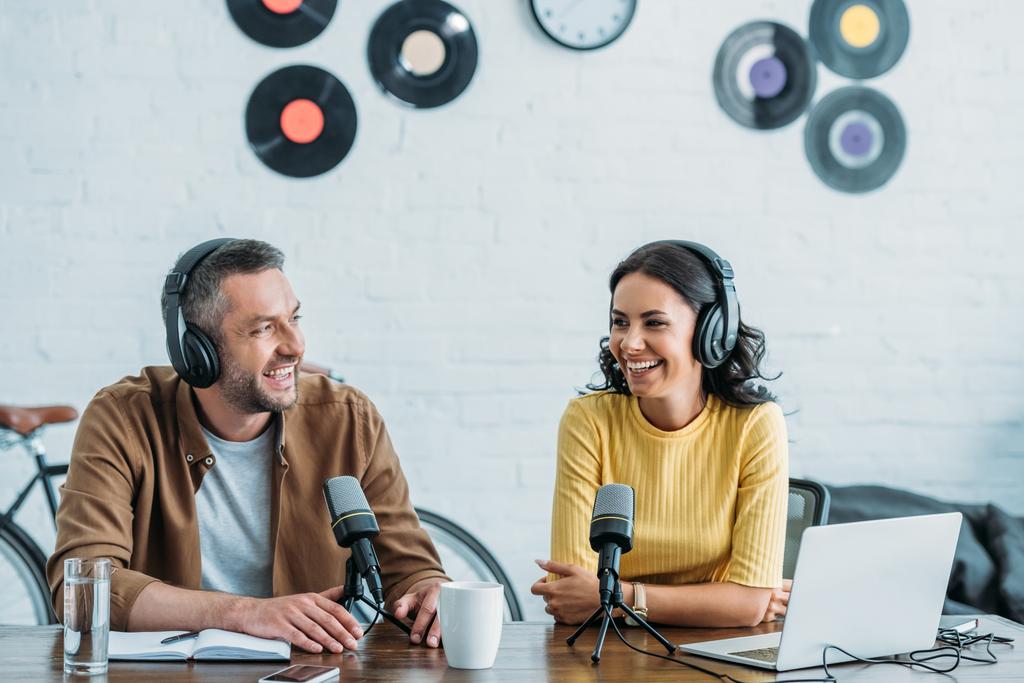 iki neşeli radyo hosts mikrofonlar yanında oturan ve stüdyoda podcast kayıt - Fotoğraf, Görsel