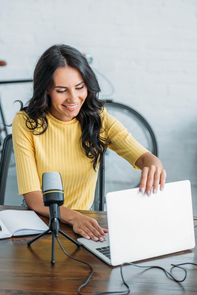 mosolygós rádiós házigazdák megnyitása laptop mellett ülve mikrofon mellett a stúdióban - Fotó, kép