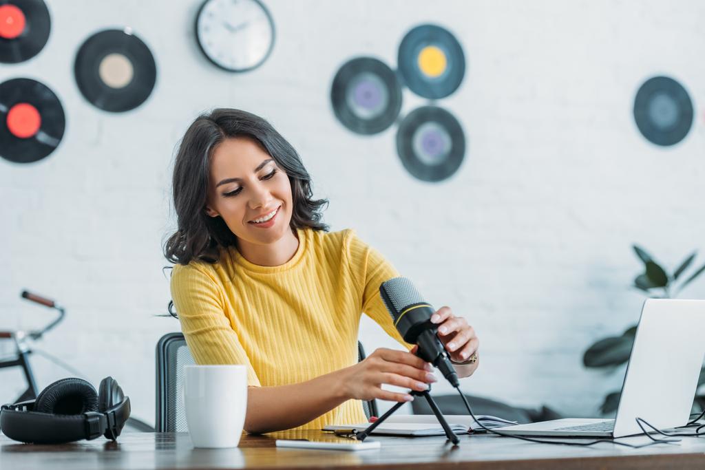 grazioso conduttore radio che regola il microfono mentre è seduto sul posto di lavoro in studio
 - Foto, immagini