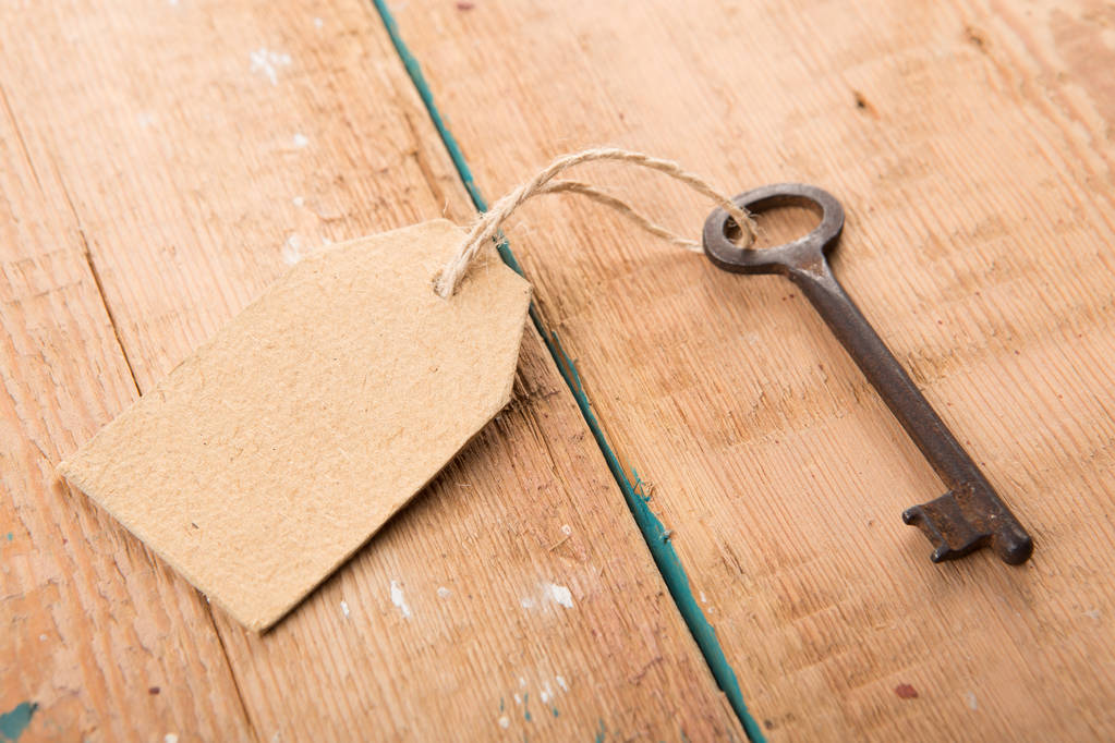 Alter rostiger Schlüssel mit Papieretikett auf dem Holzbrett - Foto, Bild