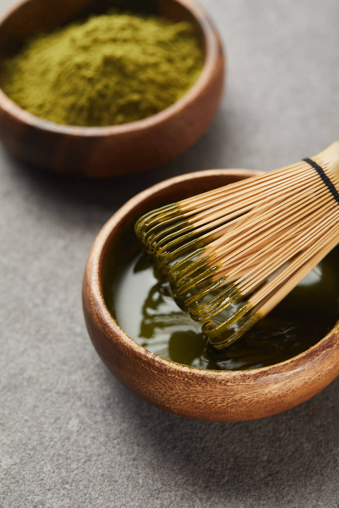 επιλεκτική εστίαση της πράσινης σκόνης μάτσα και του σύρμα από μπαμπού σε ξύλινο μπολ με τσάι - Φωτογραφία, εικόνα