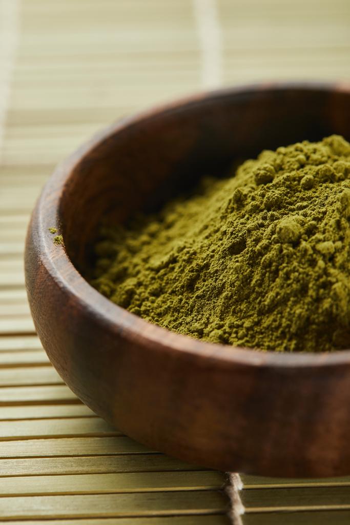 selective focus of green matcha powder in wooden bowl on table mat - Photo, Image