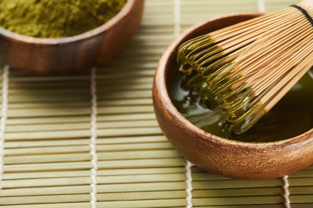 селективный фокус зеленого порошка маття и бамбукового венчика в деревянной чашке с чаем
 - Фото, изображение