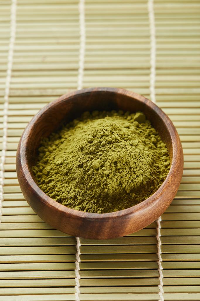 селективный фокус зеленого порошка маття в деревянной чаше на бамбуковом коврике
 - Фото, изображение
