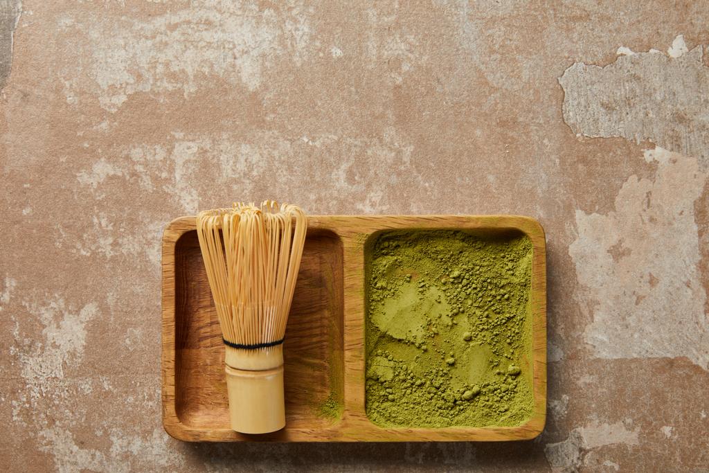 top view of matcha powder and bamboo whisk on wooden board - Photo, Image